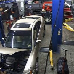 A mechanic gets his corners stuck in the hood of a car